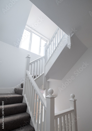 Renovated, white painted, wooden staircase with simple vertical slats, in an Edwardian house, north west London UK.