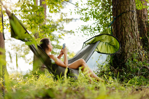 Tableau sur toile A green hammock hangs among the trees by the lake