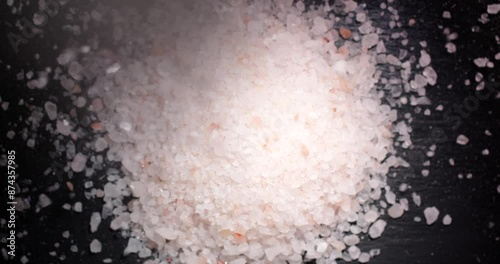 Himalayan pink salt grains falling from a height.