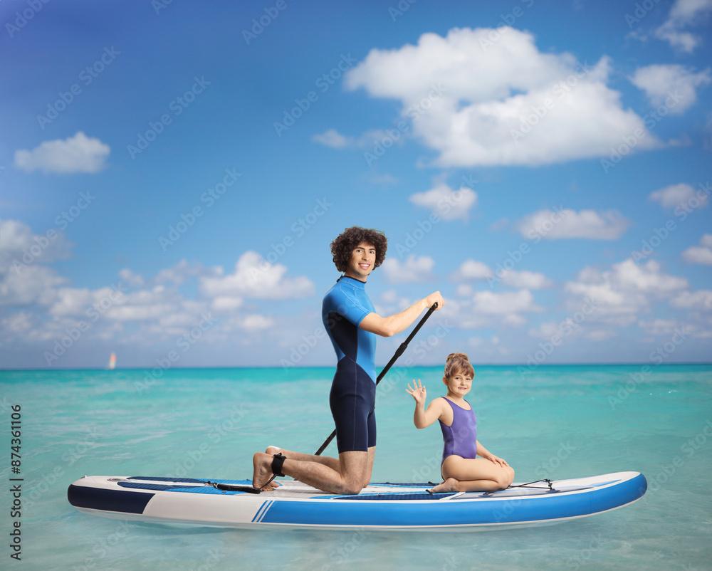 Little girl sitting on a SUP in the sea with a man Little girl sitting on a SUP in the sea with a man