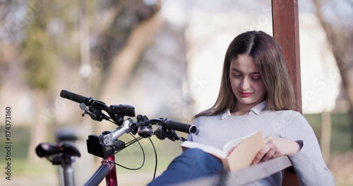 Wallpaper Mural A peaceful scene of a young woman engrossed in reading a book, seated by her bicycle in a sunny park. Torontodigital.ca