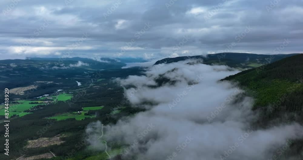 Aerial drone captures mountains adorned with lush greenery, embraced by soft clouds. Aerial drone captures mountains adorned with lush greenery, embraced by soft clouds.