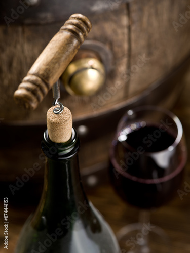 Opening a bottle of wine with a corkscrew and glass of red wine. Top view.