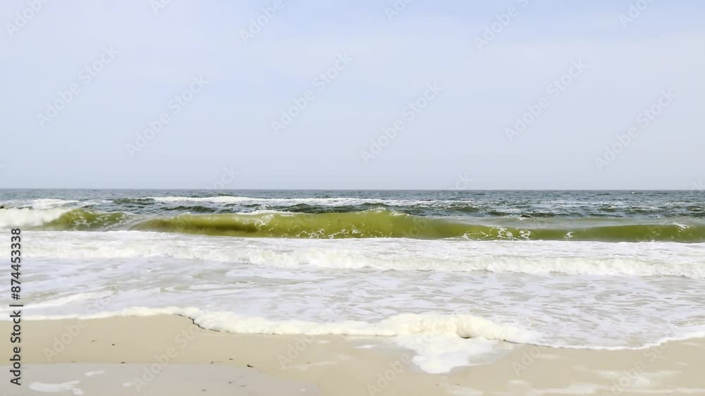 Stormy sea waves with white foam rolling on sandy beach under a sunny sky, coastal nature panoramic footage Stormy sea waves with white foam rolling on sandy beach under a sunny sky, coastal nature panoramic footage