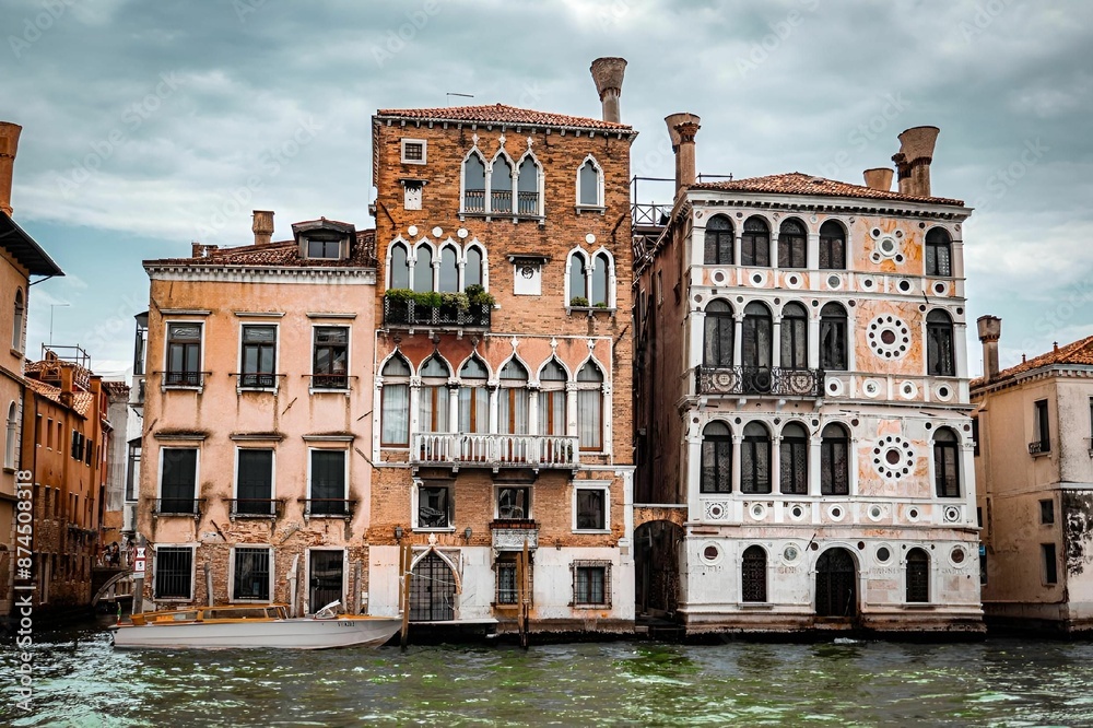 Naklejka premium Venetian buildings along the Grand Canal in Venice, Italy under a cloudy sky