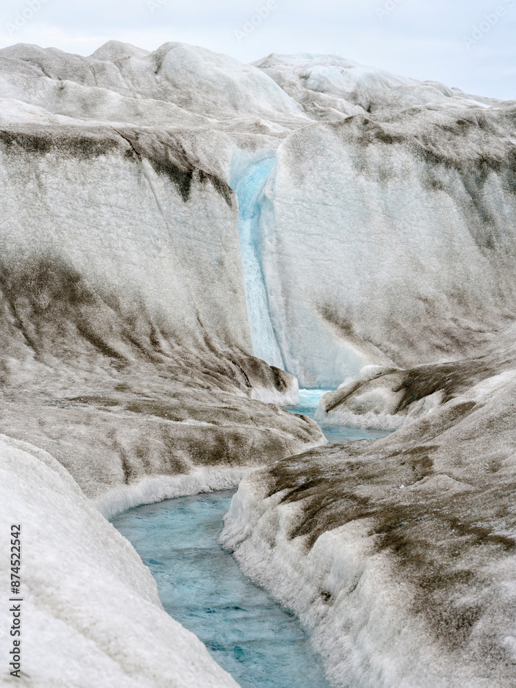 Drainage system on surface of ice sheet. Brown sediment on the ice ...