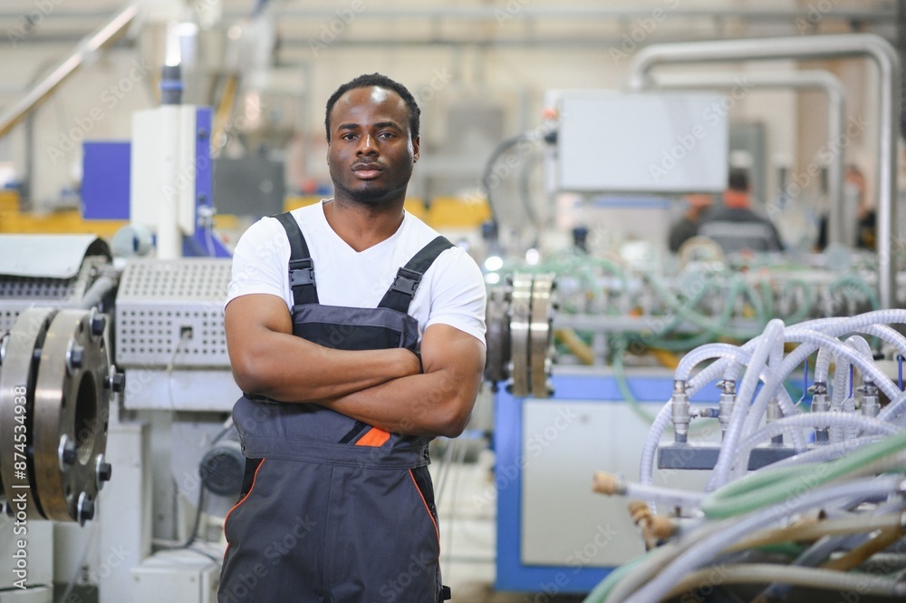 Portrait of African American male engineer in uniform and standing in industrial factory Portrait of African American male engineer in uniform and standing in industrial factory