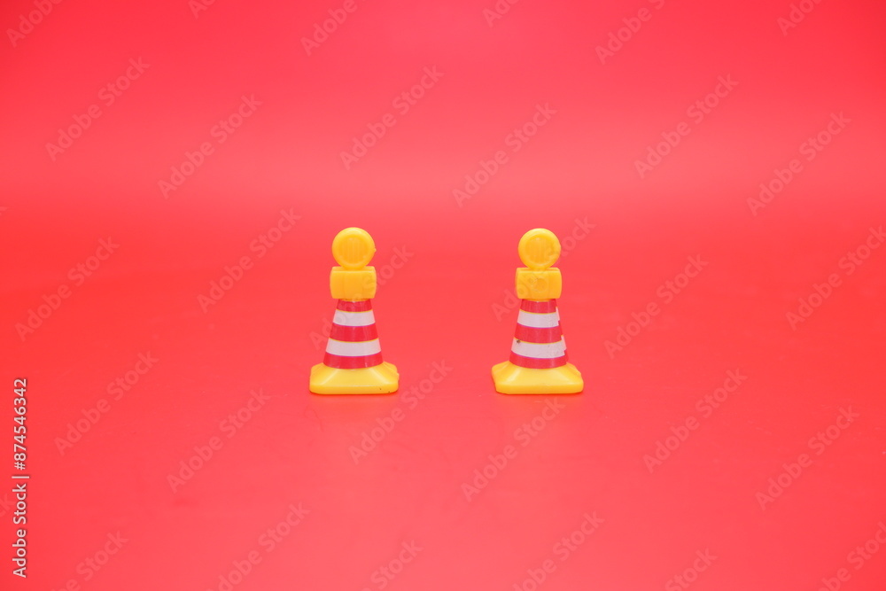traffic cone toy isolated on red background. miniature yellow traffic cone traffic cone toy isolated on red background. miniature yellow traffic cone