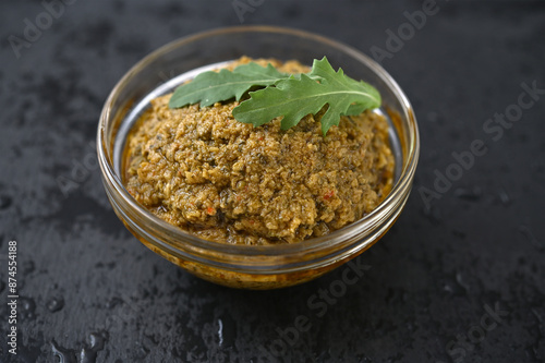 bowl with green olive and arugula topenade on a black background close-up