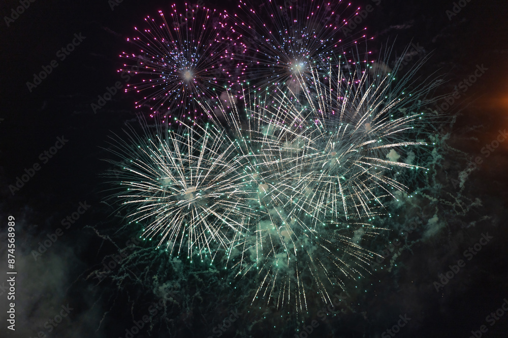 Green and purple fireworks with smoke over the black sky. Low key exposure.