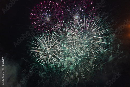 Obraz na płótnie Green and purple fireworks with smoke over the black sky. Low key exposure. w salonie
