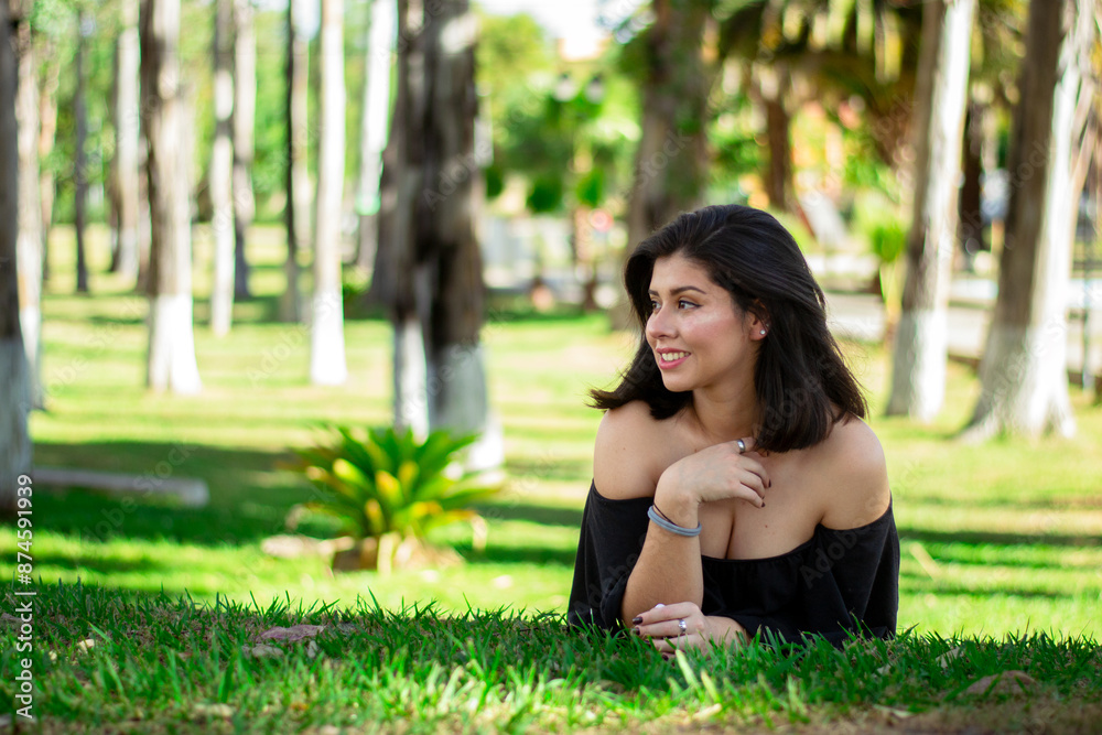 Beautiful young Hispanic woman lying on the grass looking to the side, portrait with copy space, she is happy in the park. Beautiful young Hispanic woman lying on the grass looking to the side, portrait with copy space, she is happy in the park.