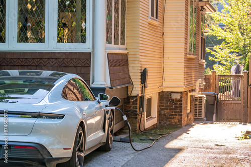green economy: close up of a high performance electric vehicle connected to a home charging station in a residential driveway