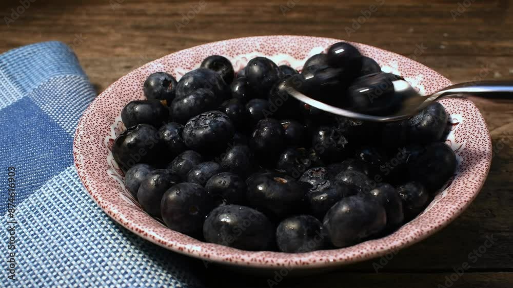 Close-up napkin bowl full of shiny fresh blueberries spoon scooping up blueberries rustic wooden background Close-up napkin bowl full of shiny fresh blueberries spoon scooping up blueberries rustic wooden background