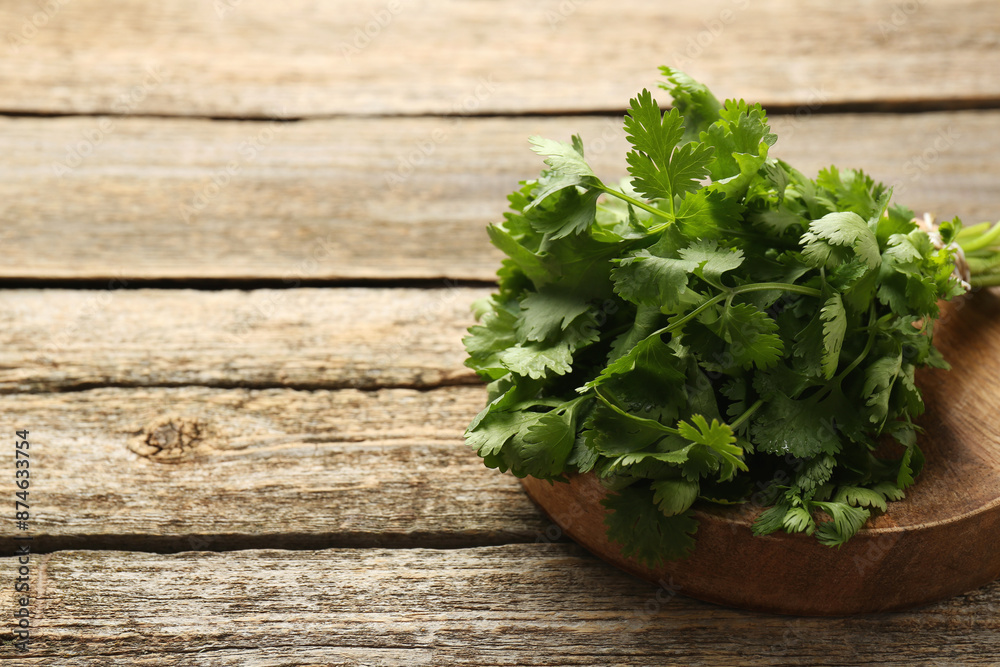 Bunch of fresh coriander on wooden table, space for text Bunch of fresh coriander on wooden table, space for text