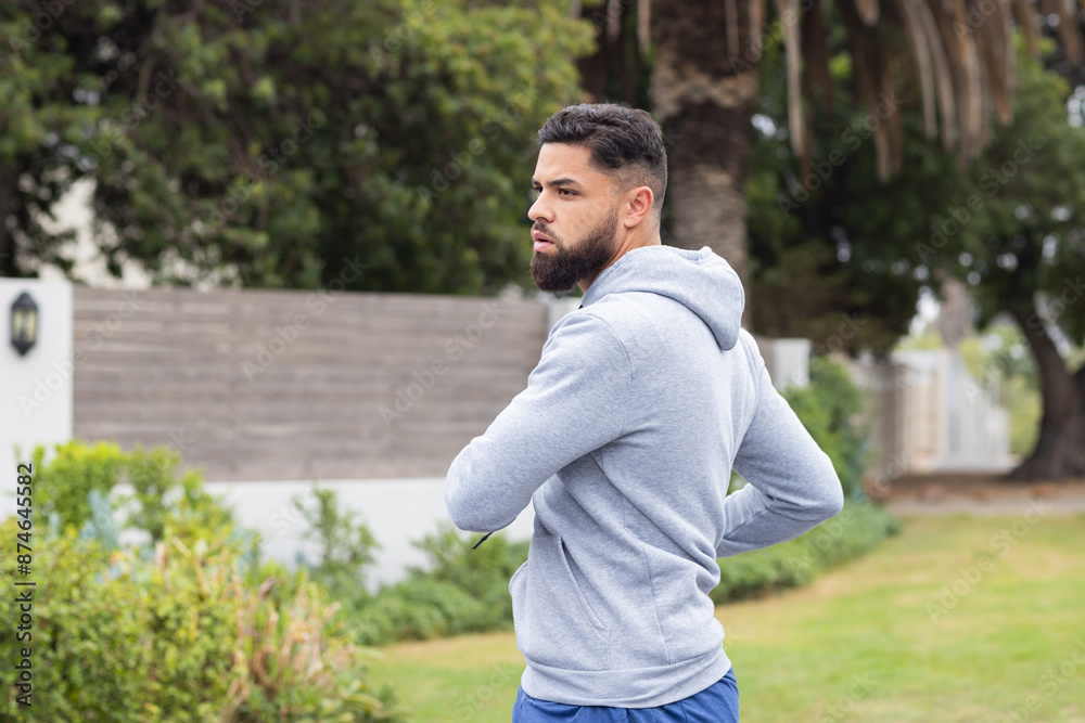 Exercising outdoors, man in hoodie stretching and preparing for workout, copy space Exercising outdoors, man in hoodie stretching and preparing for workout, copy space