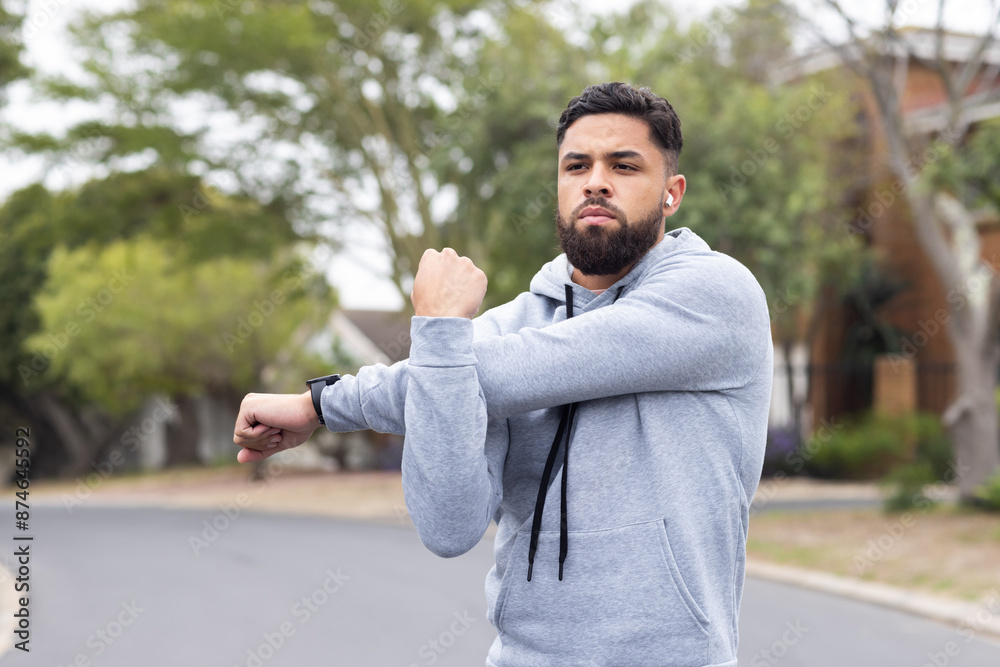 Stretching arms, man in hoodie exercising outdoors, preparing for workout, copy space Stretching arms, man in hoodie exercising outdoors, preparing for workout, copy space