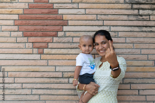 Picture of an Indian woman along with her baby showing her finger after casting vote in election. Lok sabha, vidhan sabha, polls, election commission of india, technology, democarcy, voice, choice photo