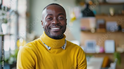 A man in a yellow sweater is smiling and posing for a picture
