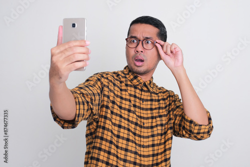 A man looking to mobile phone that he hold with shocked expression photo