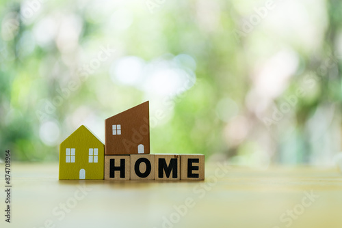 Home model placed on wood block of HOME against natural background with copy space