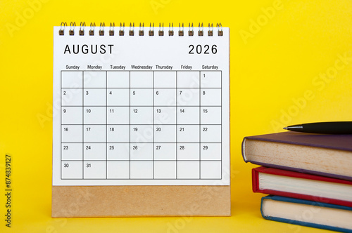 August 2026 calendar with yellow cover background and books. New month and calendar concept