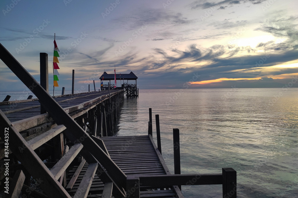 Obraz premium Enjoying the beach atmosphere at sunset on the wooden pier bridge of Maratua Island., East Kalimantan