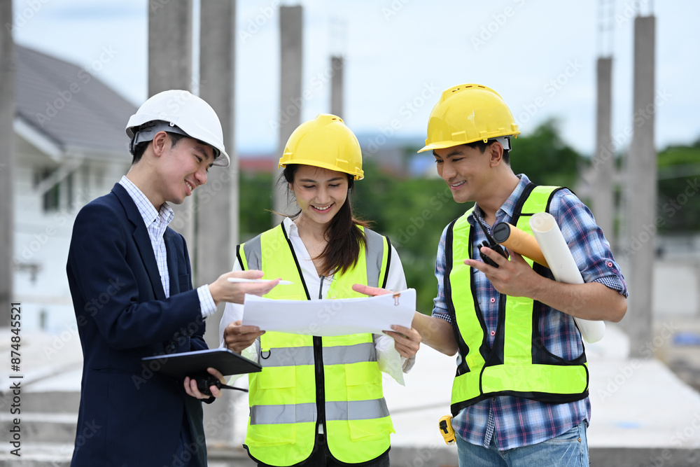 Engineering team discussing over blueprint while standing at construction site Engineering team discussing over blueprint while standing at construction site