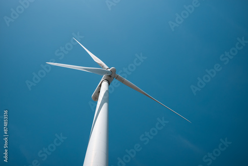 White wind turbine against blue sky. View from the ground. photo