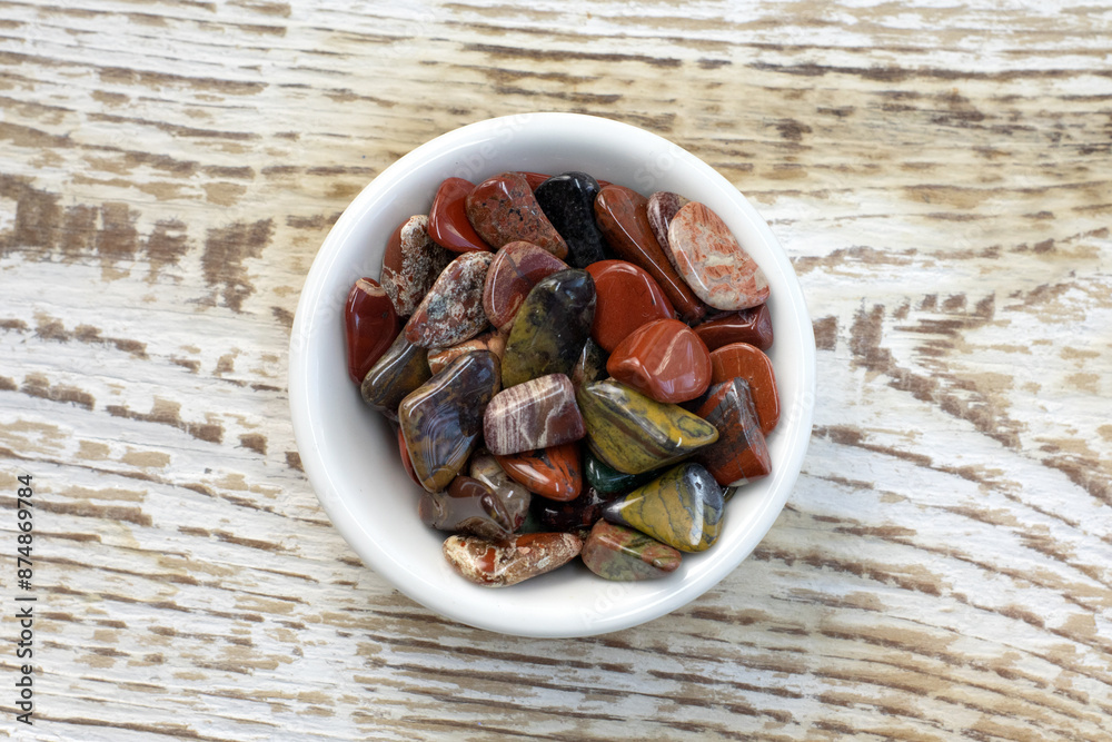 Red and multicolored jasper polished tumblestones as nice natural background on white plate Red and multicolored jasper polished tumblestones as nice natural background on white plate