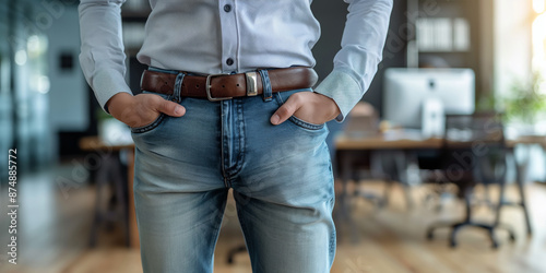 Person with hands in pockets wearing jeans and shirt in office setting. Concept of casual work attire, professionalism, and modern workplace