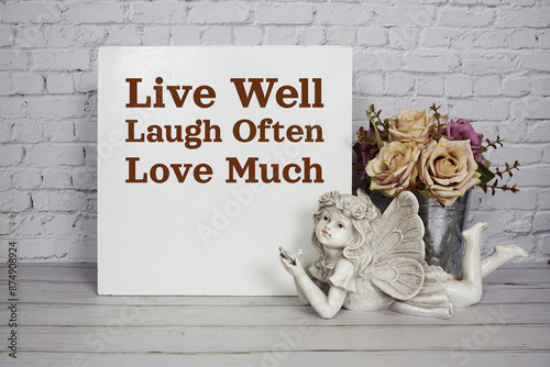 Live well laugh often love much motivational and inspiration quote with angel ceramic doll and roses flowers in metal vase decoratiom on wooden background photo