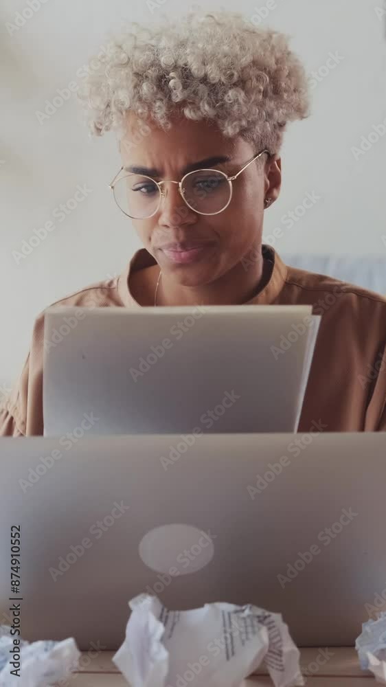 Young upset nervous African American woman throws away documents read and suffers due to financial problems and too high income taxes sits at table with laptop in office. Professional burnout
