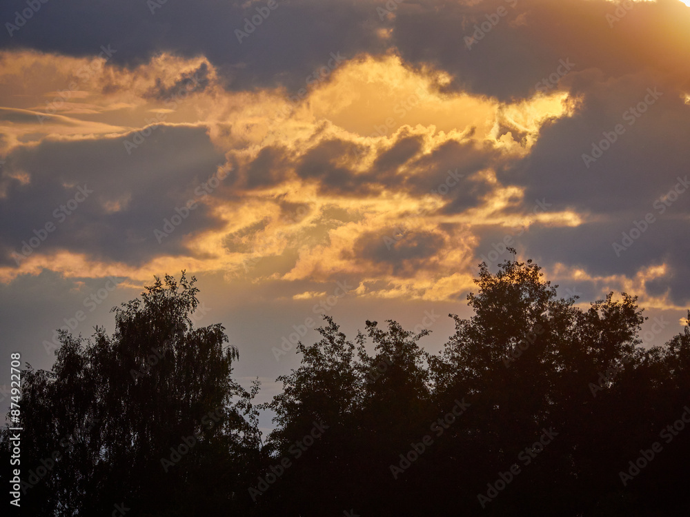 Evening landscape. Sunset sun in the clouds and dark silhouette of the forest Evening landscape. Sunset sun in the clouds and dark silhouette of the forest
