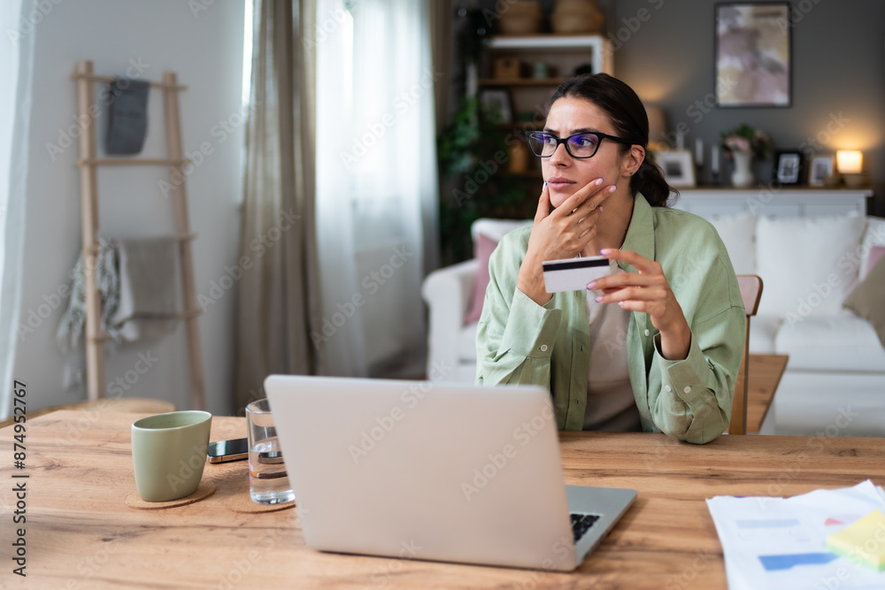 Simple living. Young woman sitting at home holding credit card having issue with online payment or shopping on internet with digital tablet. Female banking problems, overspending or finance theft. Simple living. Young woman sitting at home holding credit card having issue with online payment or shopping on internet with digital tablet. Female banking problems, overspending or finance theft.