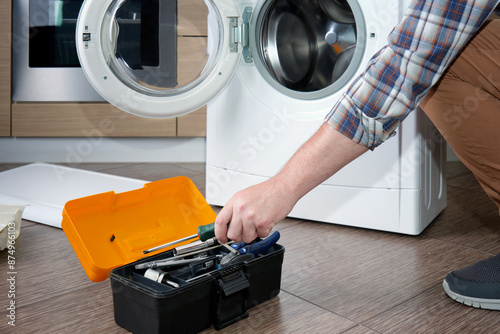 Billede på lærred A household appliance repairman disassembling a washing machine with a screwdriver