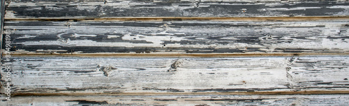 The white paint was peeling off the old boards. The painted boards are aged and weathered.