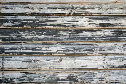 The white paint was peeling off the old boards. The painted boards are aged and weathered.