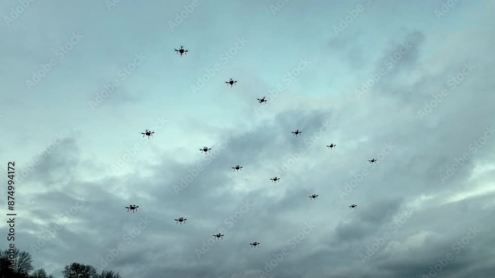 Formation of drones against a cloudy sky. Multiple drones fly in a synchronized formation against a backdrop of a cloudy sky.