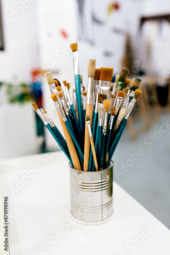 Art brushes in a metal container on a white table photo