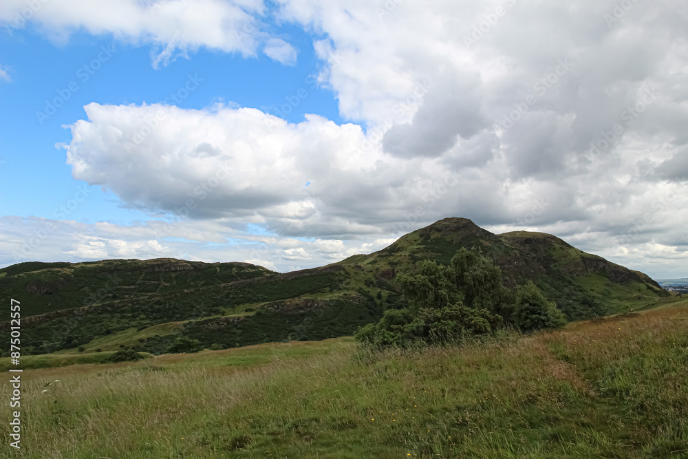 View of Arthur’s Seat from Salisbury Crags on blue sky and cloud background in Edinburgh Scotland View of Arthur’s Seat from Salisbury Crags on blue sky and cloud background in Edinburgh Scotland