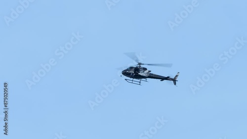 A black helicopter is flying in the sky