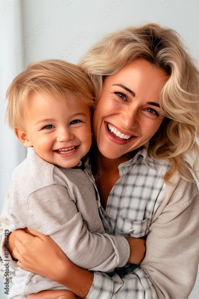 Happy mother holding her smiling blonde toddler, both looking joyful and affectionate in a close-up portrait, highlighting family love and bonding. Happy mother holding her smiling blonde toddler, both looking joyful and affectionate in a close-up portrait, highlighting family love and bonding.