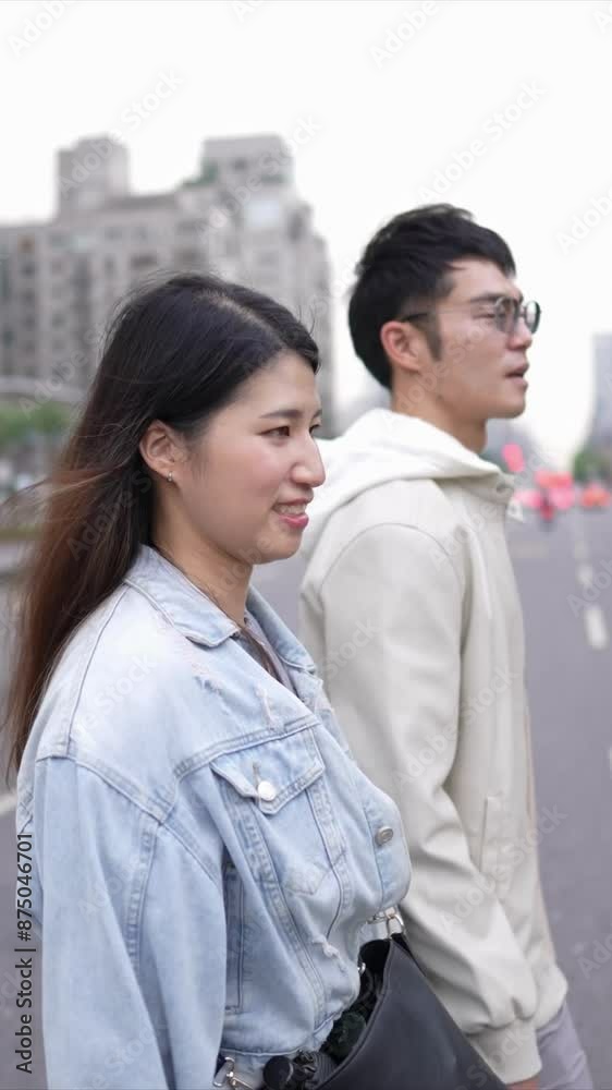 A vertical video of a young Taiwanese couple in their twenties walking through the streets of Xinyi District, Taipei City on a spring afternoon. The man is wearing a hoodie A vertical video of a young Taiwanese couple in their twenties walking through the streets of Xinyi District, Taipei City on a spring afternoon. The man is wearing a hoodie