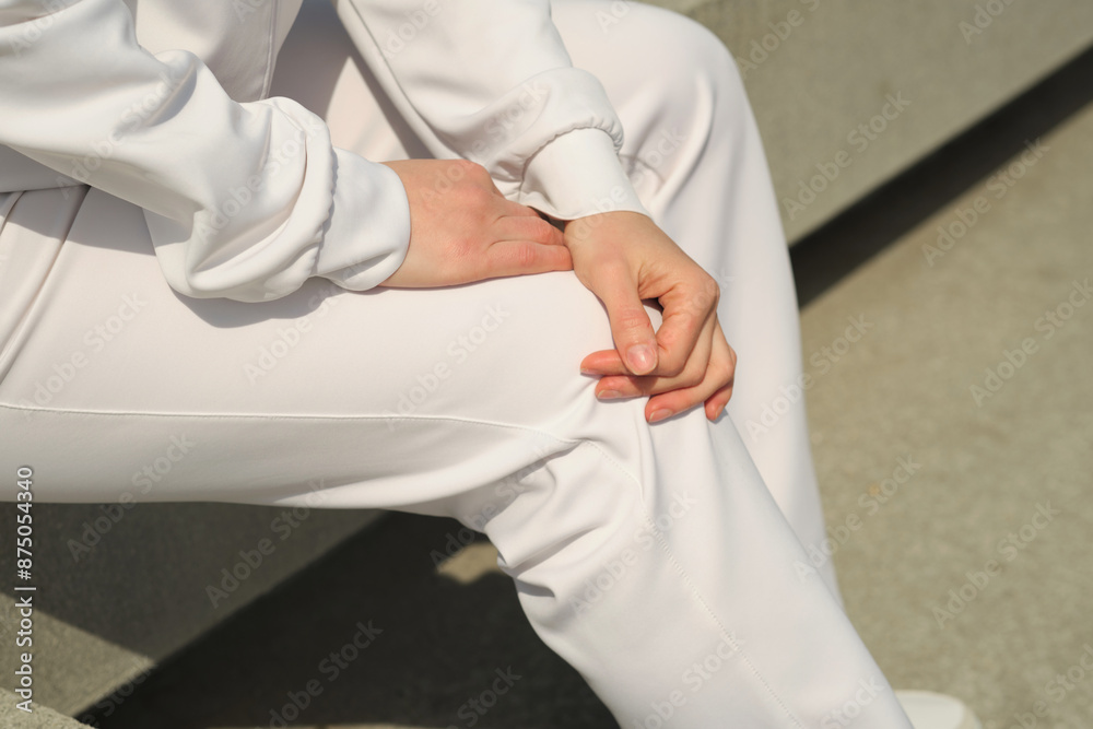 Obraz premium Close-up of hands resting on a knee, dressed in white athletic wear, capturing a moment of stillness. Concept: Emphasizing the importance of taking breaks and finding moments of calm in a busy, active