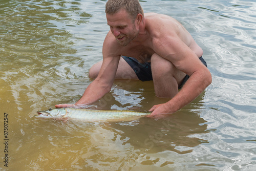 Man holding a Muskie, pike fish, caught on shore allegheny state forest kinzua beach Pa, selective focus portrait background image of man holding a fish photo