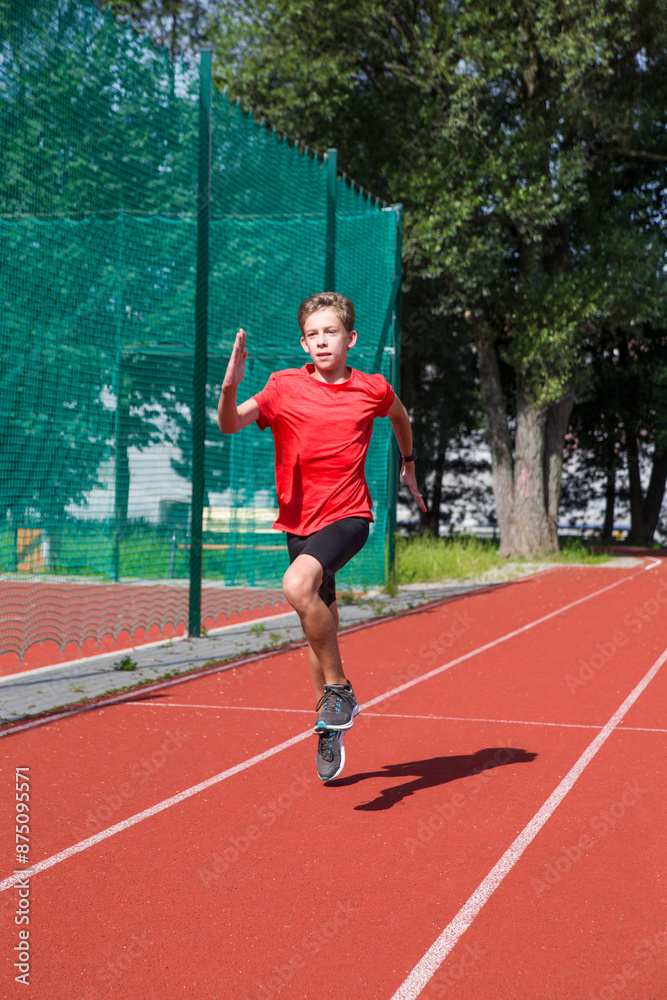 Fototapeta premium An athlete performs special running exercises at the stadium. 