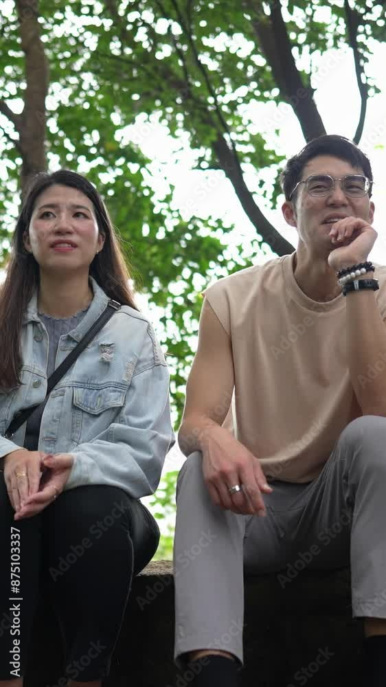 A vertical slow-motion video of a young Taiwanese couple in their twenties sitting and talking in the mountains of Xinyi District, Taipei City. The man is wearing a sleeveless top A vertical slow-motion video of a young Taiwanese couple in their twenties sitting and talking in the mountains of Xinyi District, Taipei City. The man is wearing a sleeveless top