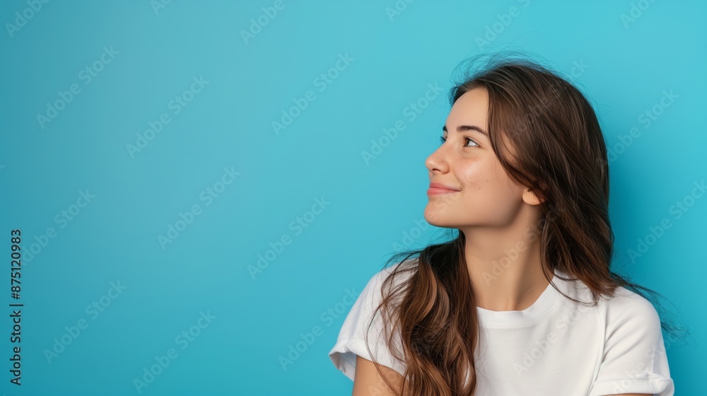 A woman with long brown hair is smiling and looking up at the sky. The blue background adds a sense of calmness and serenity to the scene A woman with long brown hair is smiling and looking up at the sky. The blue background adds a sense of calmness and serenity to the scene