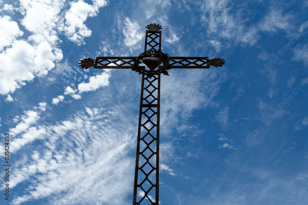 Iron cross depicting the sacred heart of Jesus on a sunny blue sky background. Croix de fer représentant le cœur sacré de Jésus sur fond de ciel bleu ensoleillé. Iron cross depicting the sacred heart of Jesus on a sunny blue sky background. Croix de fer représentant le cœur sacré de Jésus sur fond de ciel bleu ensoleillé.